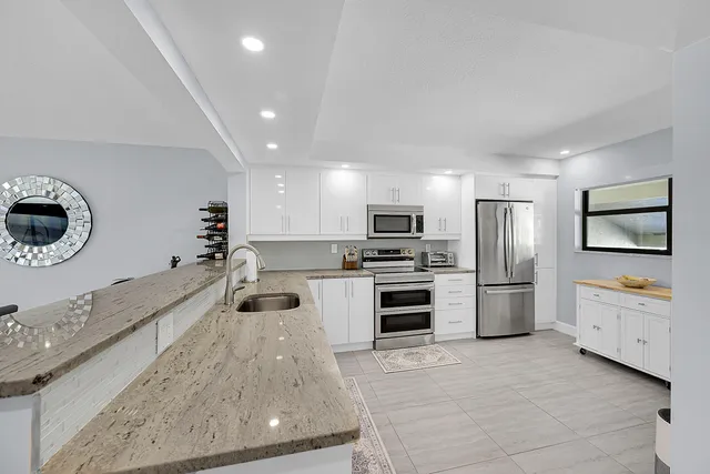 a kitchen with stainless steel appliances granite countertop a sink a stove and a refrigerator