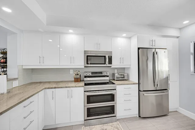 a kitchen with white cabinets and stainless steel appliances