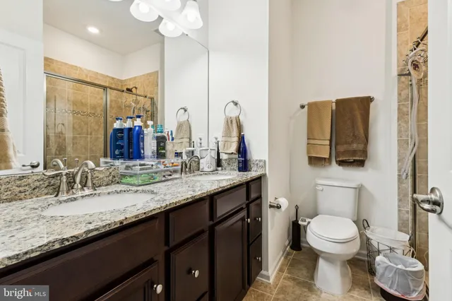 a bathroom with a granite countertop toilet sink and mirror