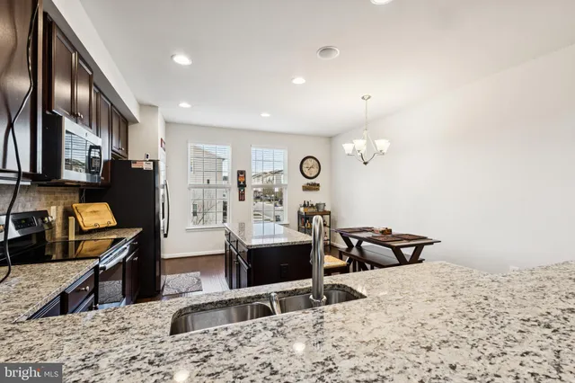 a view of a kitchen with kitchen island granite countertop a refrigerator stove microwave and sink