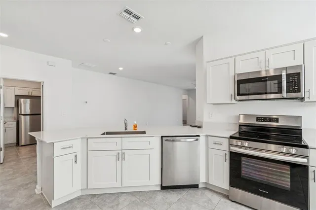 a large kitchen with stainless steel appliances granite countertop a stove a sink and a microwave