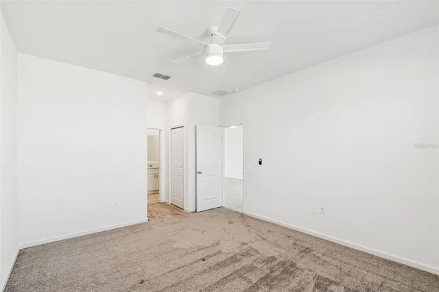 an empty room with a ceiling fan and window
