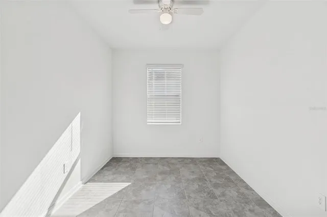an empty room with a ceiling fan and a window