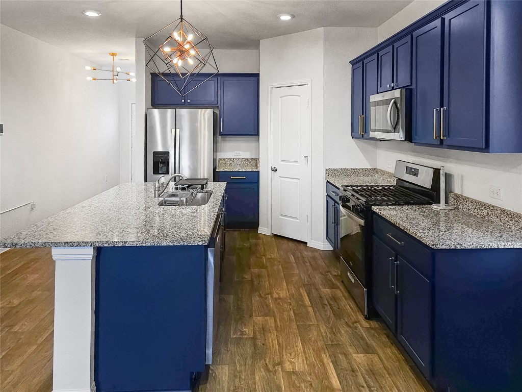 410 Inks Lane Kyle, TX 78640 - Photo 2 of 20 Kitchen featuring blue cabinets, appliances with stainless steel finishes, decorative light fixtures, an island with sink, and recessed lighting