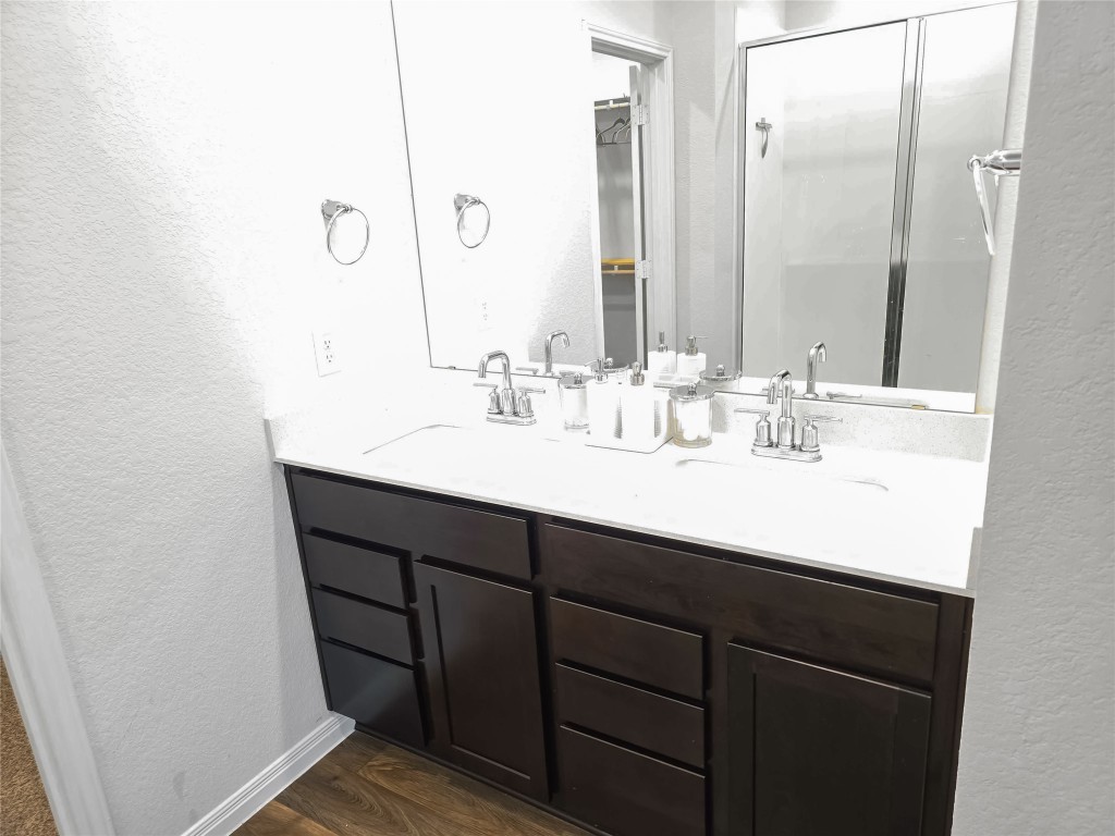 410 Inks Lane Kyle, TX 78640 - Photo 10 of 20 Master Bathroom with a textured wall, double vanity, a stall shower, and dark wood-style flooring