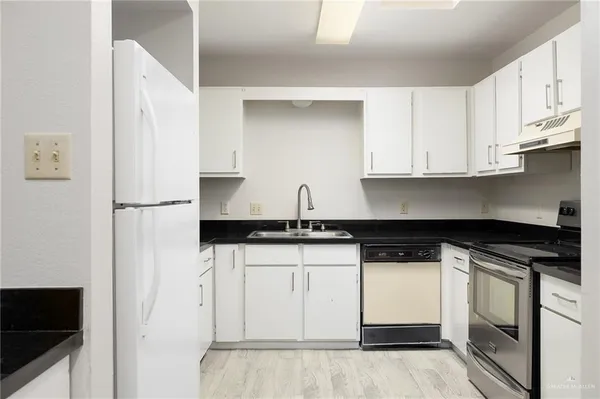 a kitchen with stainless steel appliances granite countertop a refrigerator and white cabinets