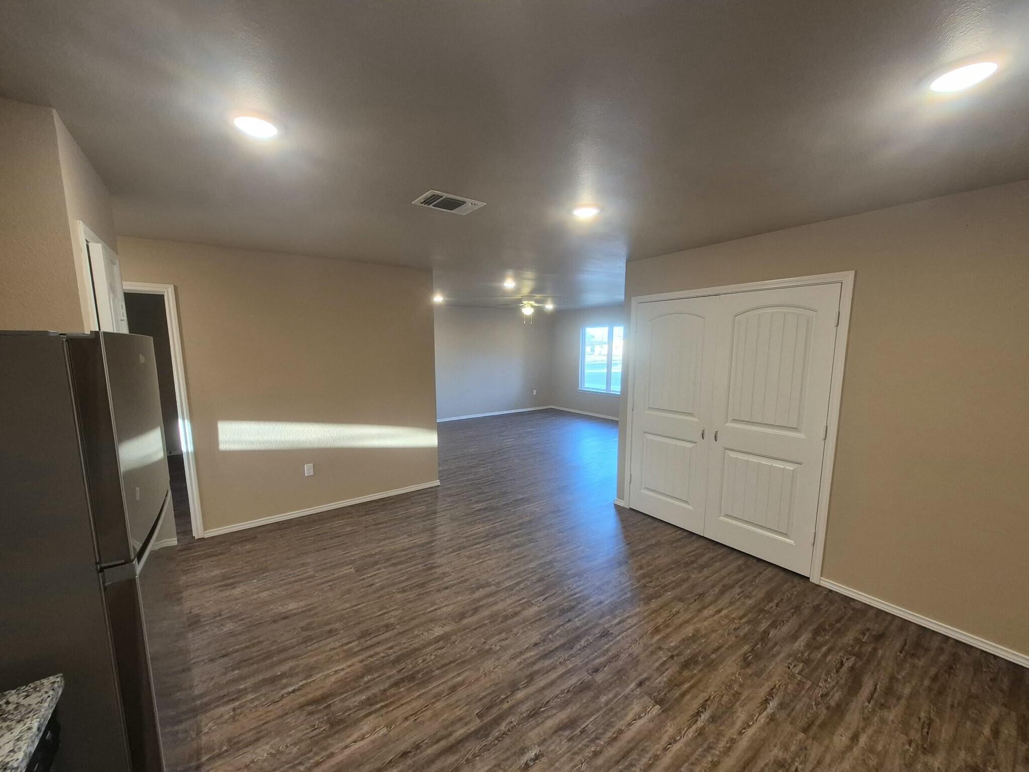 2506 Avenue P Lubbock, TX 79411 - Photo 2 of 11 an empty room with wooden floor and a refrigerator
