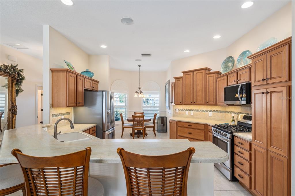 2416 Boiling Springs Court The Villages, FL 32162 - Photo 3 of 41 a kitchen with stainless steel appliances granite countertop a stove top oven a sink a dining table and chairs