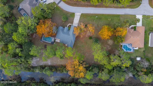 an aerial view of residential house with outdoor space and trees all around