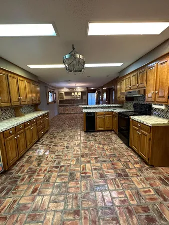 a large kitchen with stainless steel appliances granite countertop a stove granite counter tops and white cabinets
