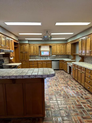 a kitchen with stainless steel appliances granite countertop a stove a sink dishwasher and cabinets with wooden floor