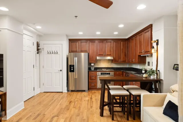 a kitchen with granite countertop a refrigerator a stove a sink a dining table and chairs