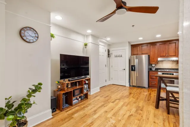 a living room with stainless steel appliances furniture a flat screen tv and a kitchen view