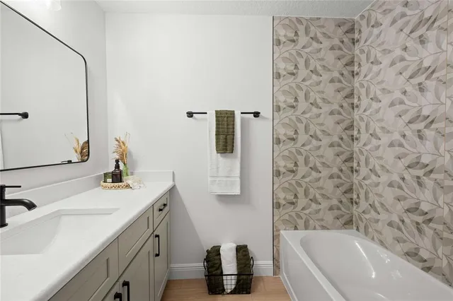 a bathroom with a sink and mirror with bathtub