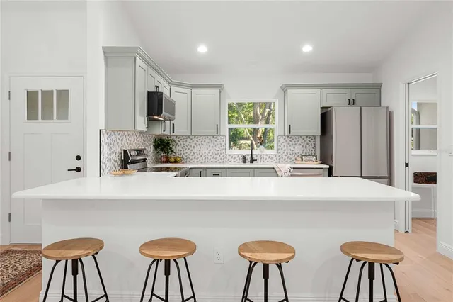 a kitchen with stainless steel appliances a white table chairs and a refrigerator