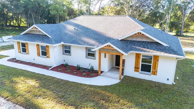 a view of a white house with a big yard and large trees