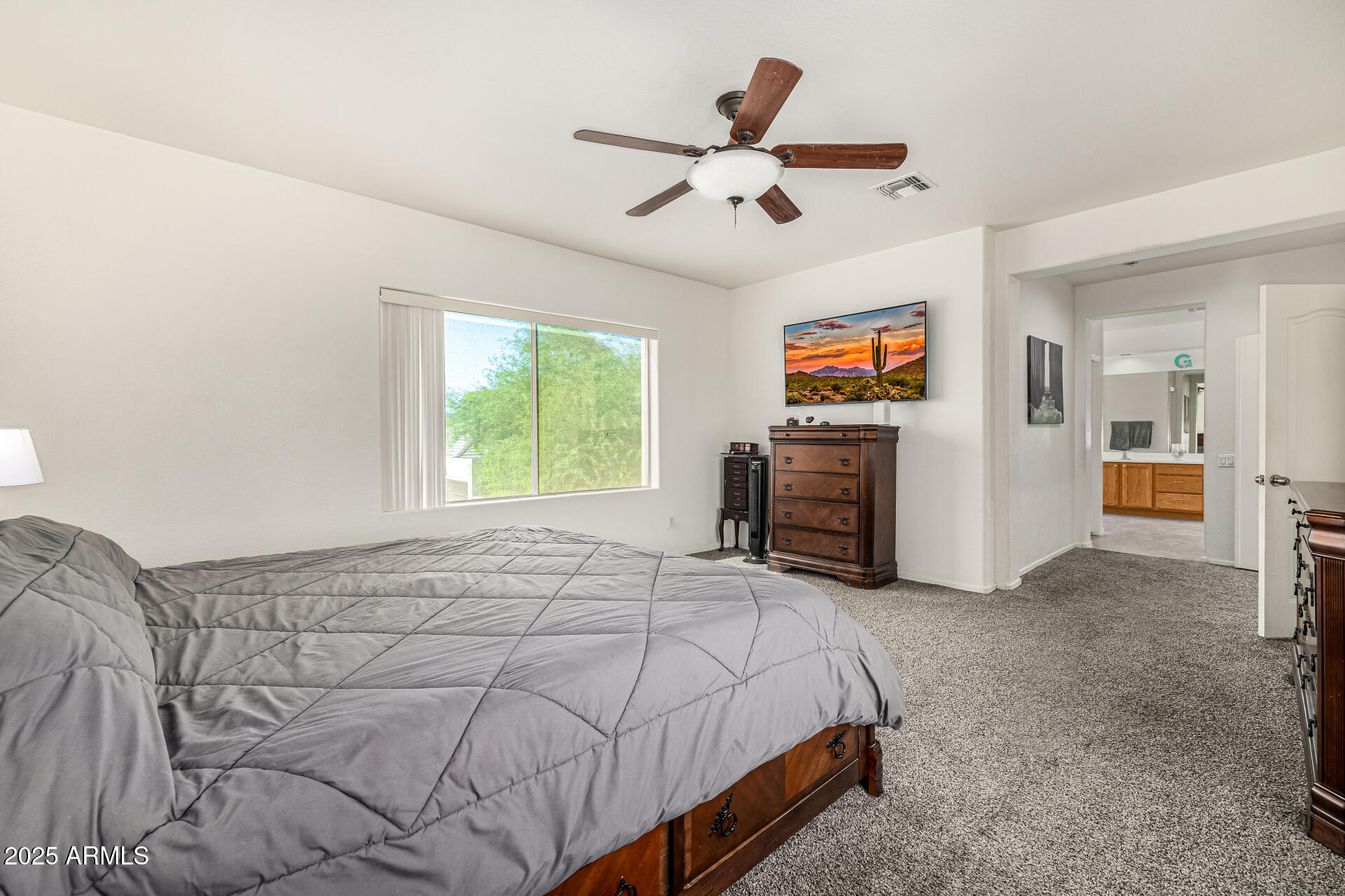 2026 North Rascon Loop Phoenix, AZ 85037 - Photo 15 of 38 a spacious bedroom with a bed and a ceiling fan