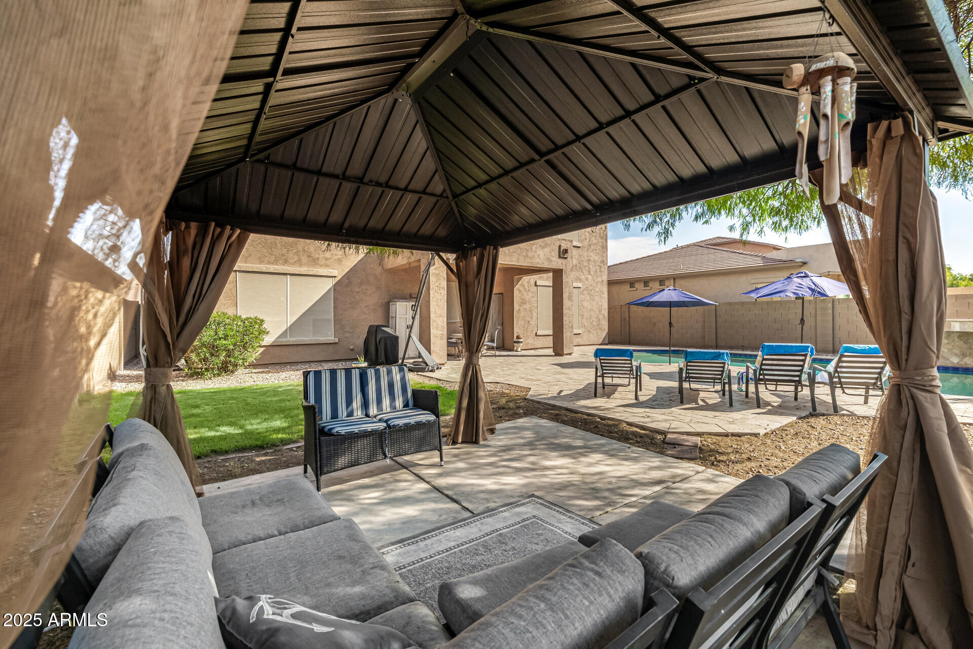 2026 North Rascon Loop Phoenix, AZ 85037 - Photo 27 of 38 a view of patio with table and chairs under an umbrella with a small yard