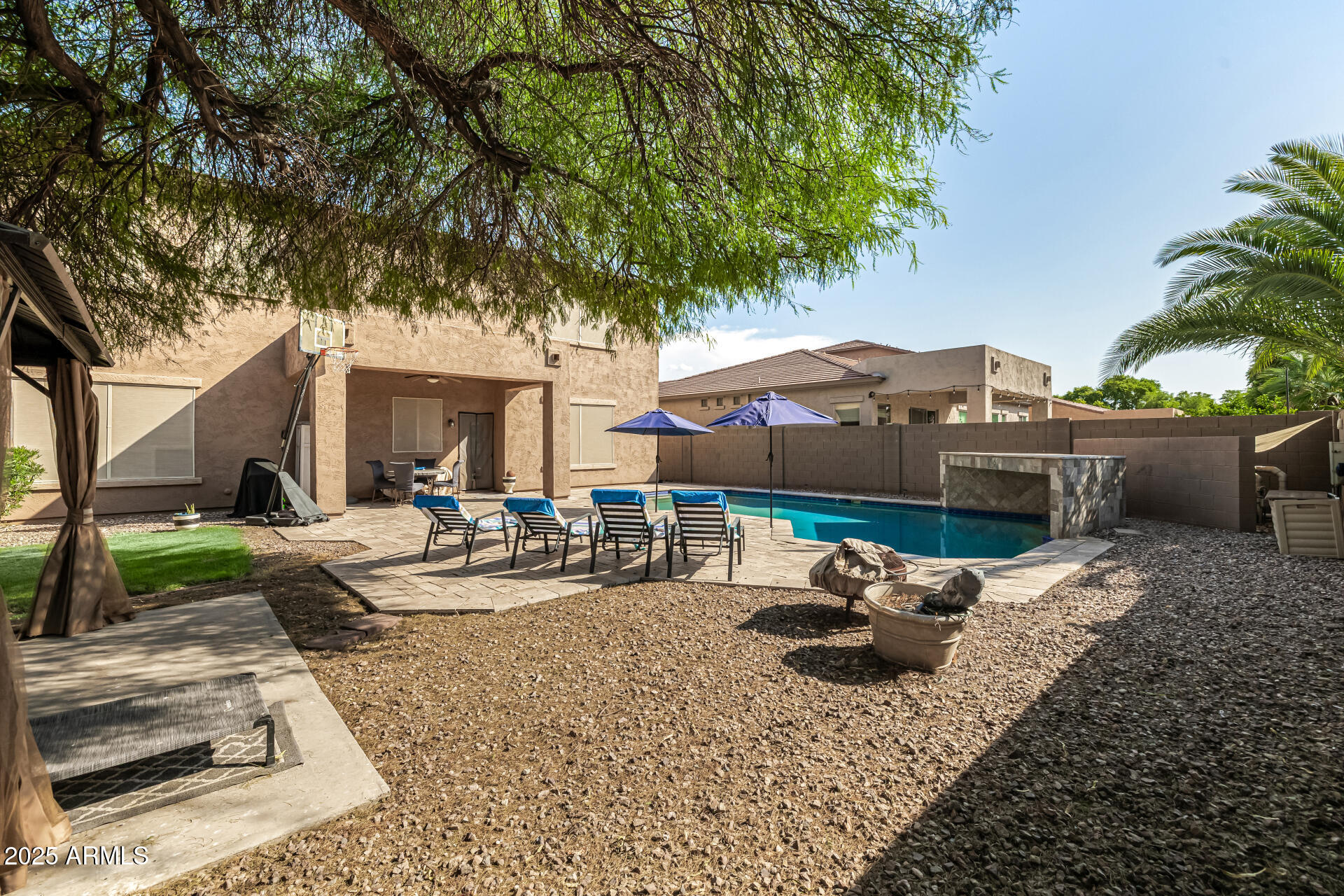 2026 North Rascon Loop Phoenix, AZ 85037 - Photo 28 of 38 a backyard of a house with table and chairs under an umbrella