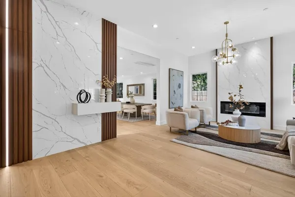 a room with lots of white furniture and chandelier