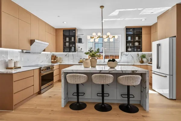 a kitchen with stainless steel appliances granite countertop a sink a stove a refrigerator and chairs