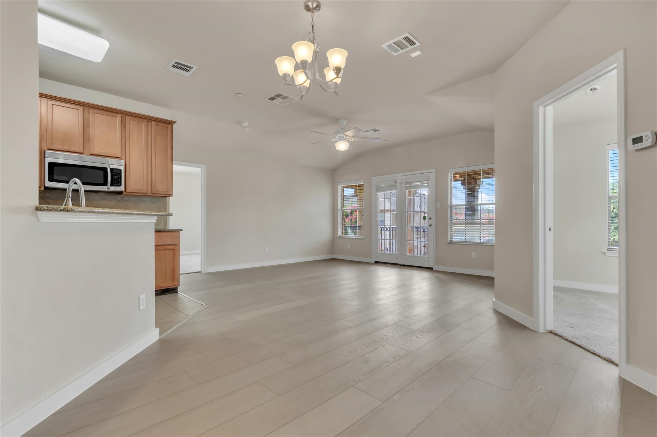 14815 Avery Ranch Boulevard, Unit 2A Austin, TX 78717 - Photo 2 of 27 An airy living space features warm flooring, vaulted ceilings, and convenient outdoor access.