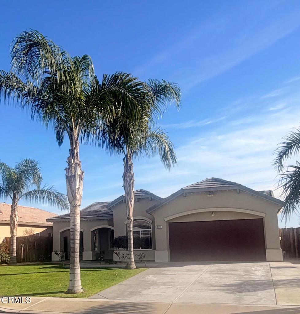 a front view of a house with a garden and palm trees