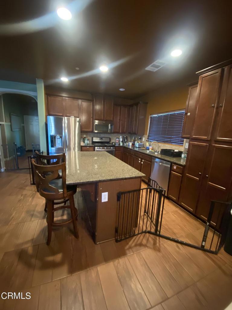 9116 Kellyann Street Bakersfield, CA 93313 - Photo 12 of 37 a kitchen with stainless steel appliances granite countertop a table chairs and a refrigerator