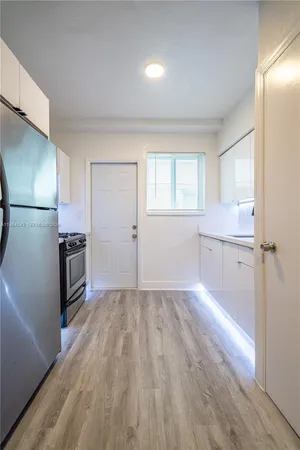 a view of a kitchen with a sink refrigerator and wooden floor