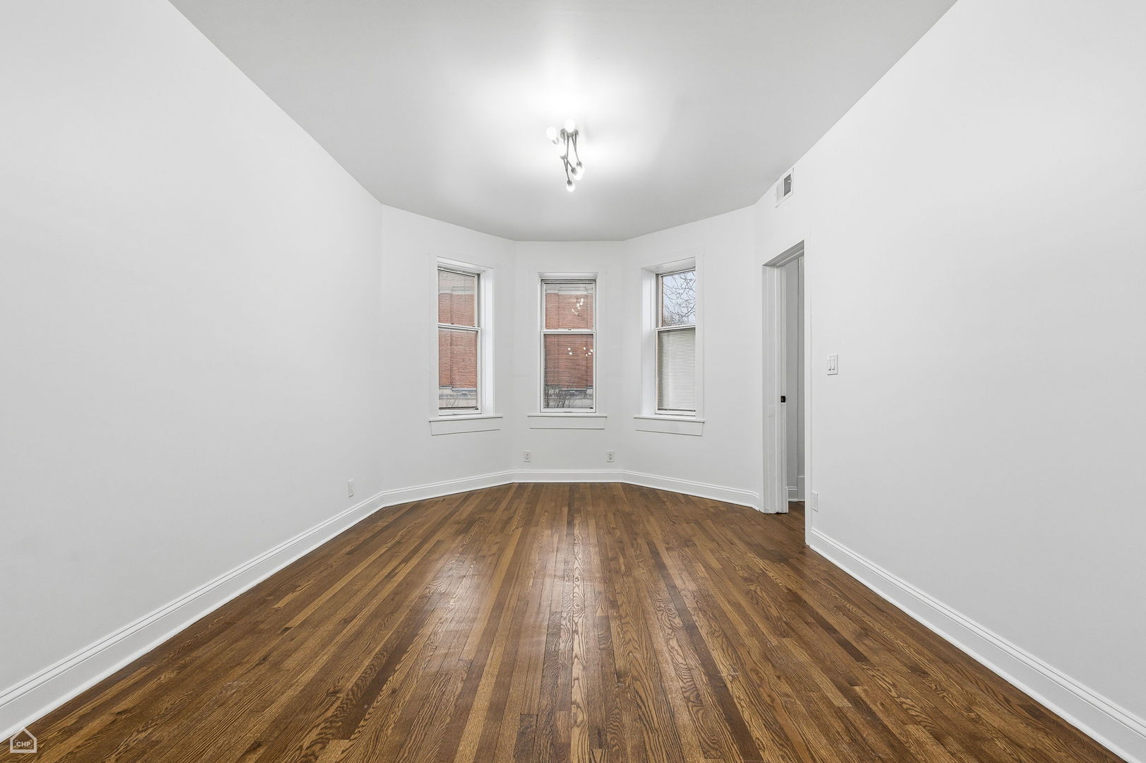 5250 West Grace Street, Unit 2 Chicago, IL 60641 - Photo 7 of 12 an empty room with wooden floor chandelier and windows