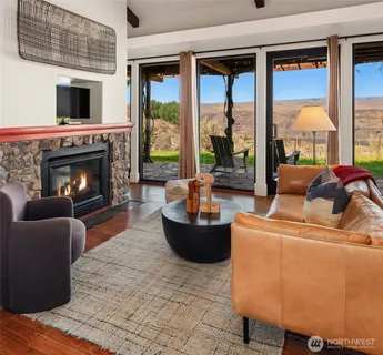 a living room with a fireplace a flat screen tv and a floor to ceiling window