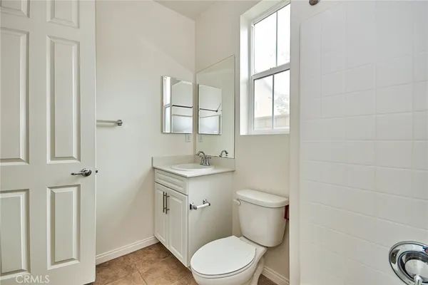 a bathroom with a toilet a sink a mirror and a window