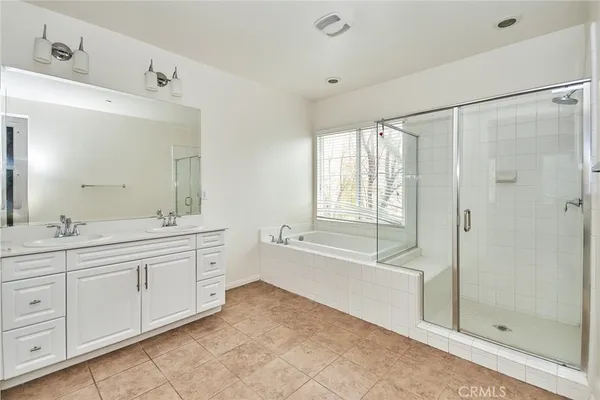 a spacious bathroom with a double vanity sink a mirror a bathtub and next to a window