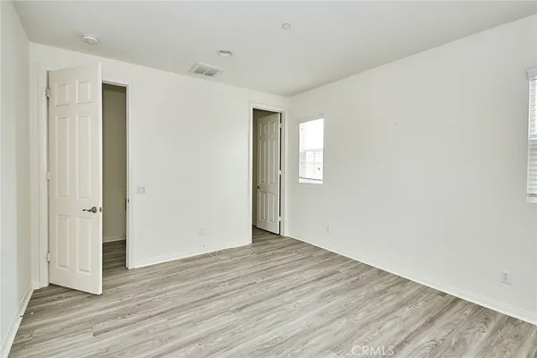 a view of an empty room with wooden floor and closet