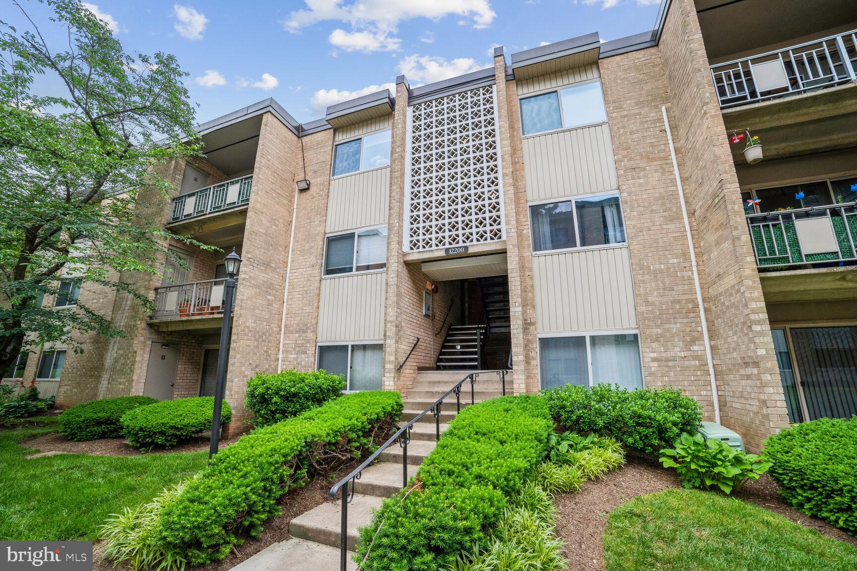 12200 Braxfield Court, Unit 209 Rockville, MD 20852 - Photo 1 of 17 a front view of a brick house with a yard and plants