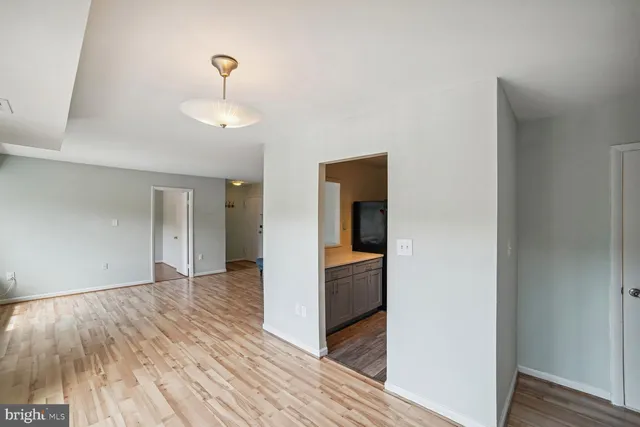 a view of a hallway with wooden floor and a bathroom