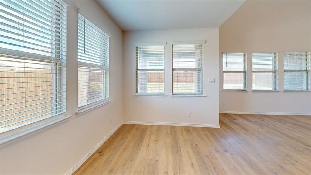 1306 Colonial Bluff Lane Princeton, TX 75407 - Photo 6 of 27 Spacious interior featuring wood-finish flooring, multiple windows with blinds, and white baseboards