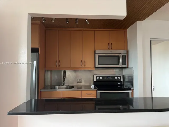 a kitchen with stainless steel appliances granite countertop a refrigerator and a stove top oven