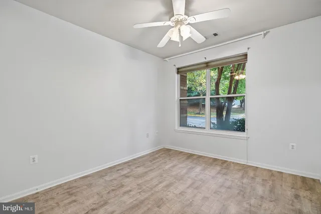 an empty room with a window and a fan
