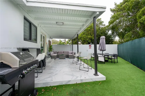 an outdoor sitting area with couch and a grill