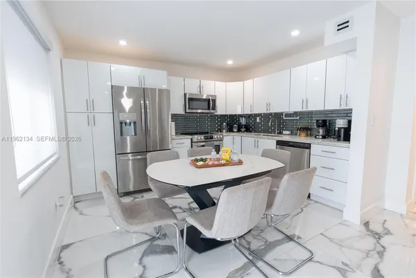 a kitchen with stainless steel appliances kitchen island granite countertop a sink a stove a refrigerator cabinets and chairs