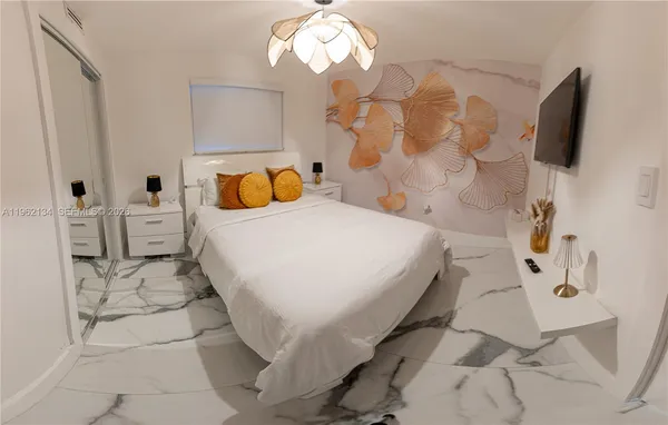 a bedroom with a bed and a flat tv screen on dresser