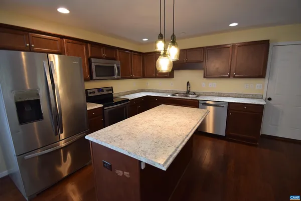 a kitchen with stainless steel appliances granite countertop a refrigerator a sink a stove a microwave and island