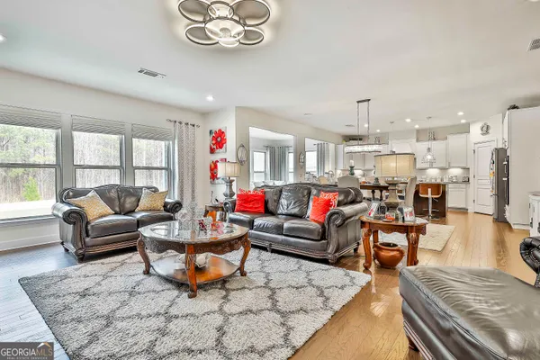 a view of a dining room and livingroom with furniture wooden floor appliances and a chandelier