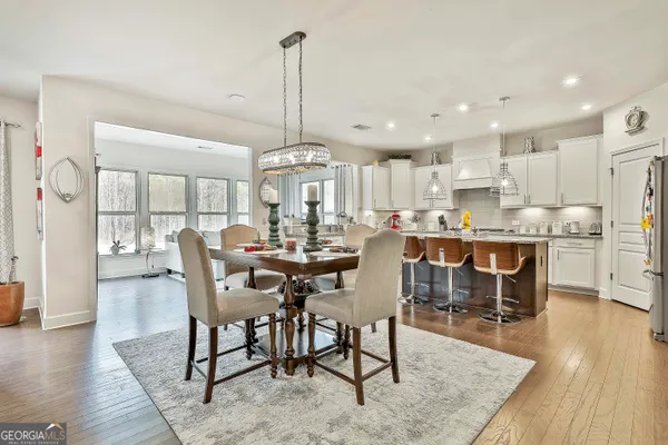 a kitchen with stainless steel appliances granite countertop a stove a sink a refrigerator and white cabinets with wooden floor