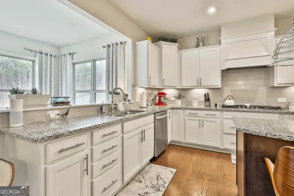 a kitchen with stainless steel appliances granite countertop a table chairs and a refrigerator