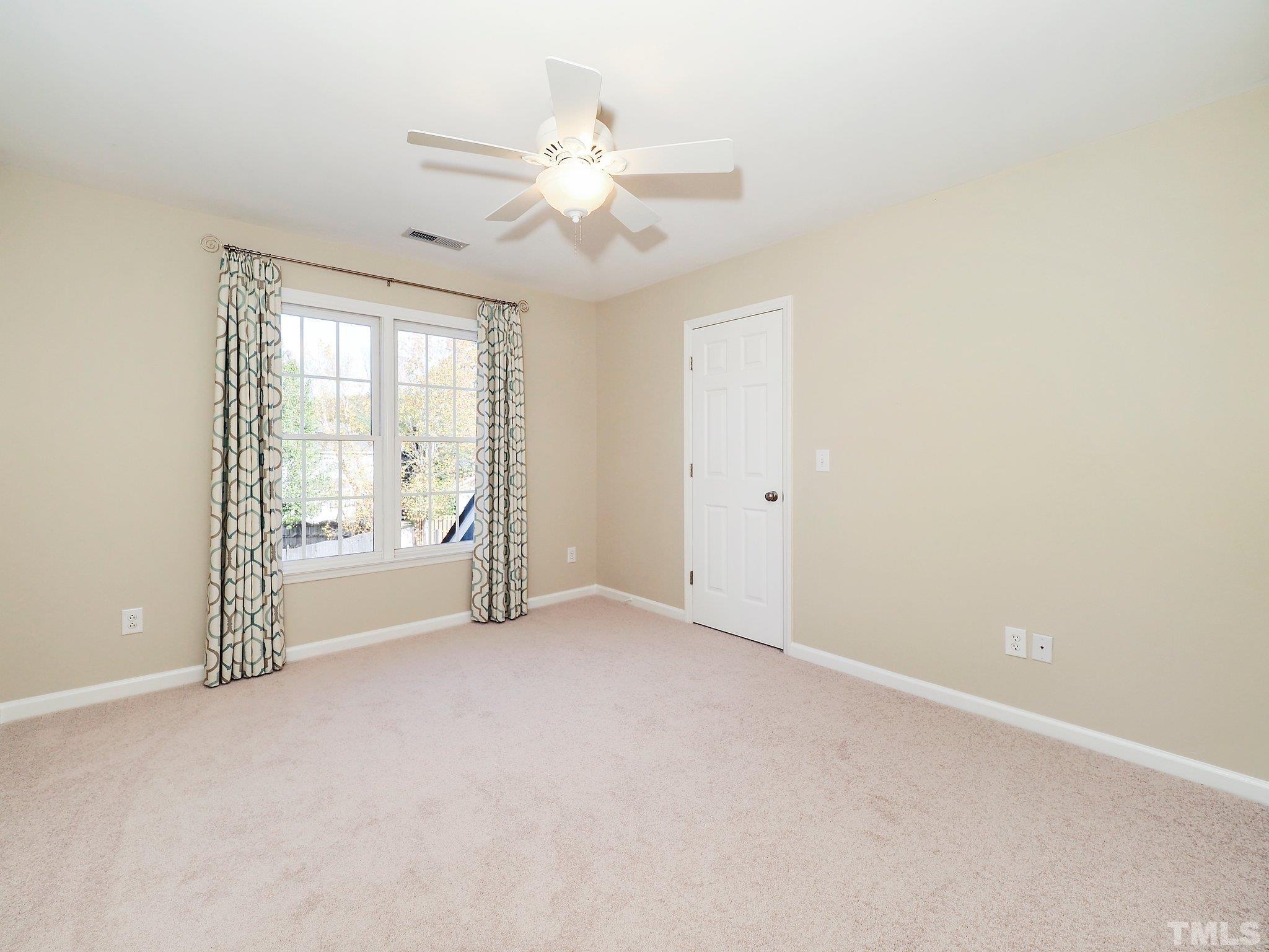 703 Haddon Hall Drive Apex, NC 27502 - Photo 32 of 49 an empty room with chandelier fan and windows