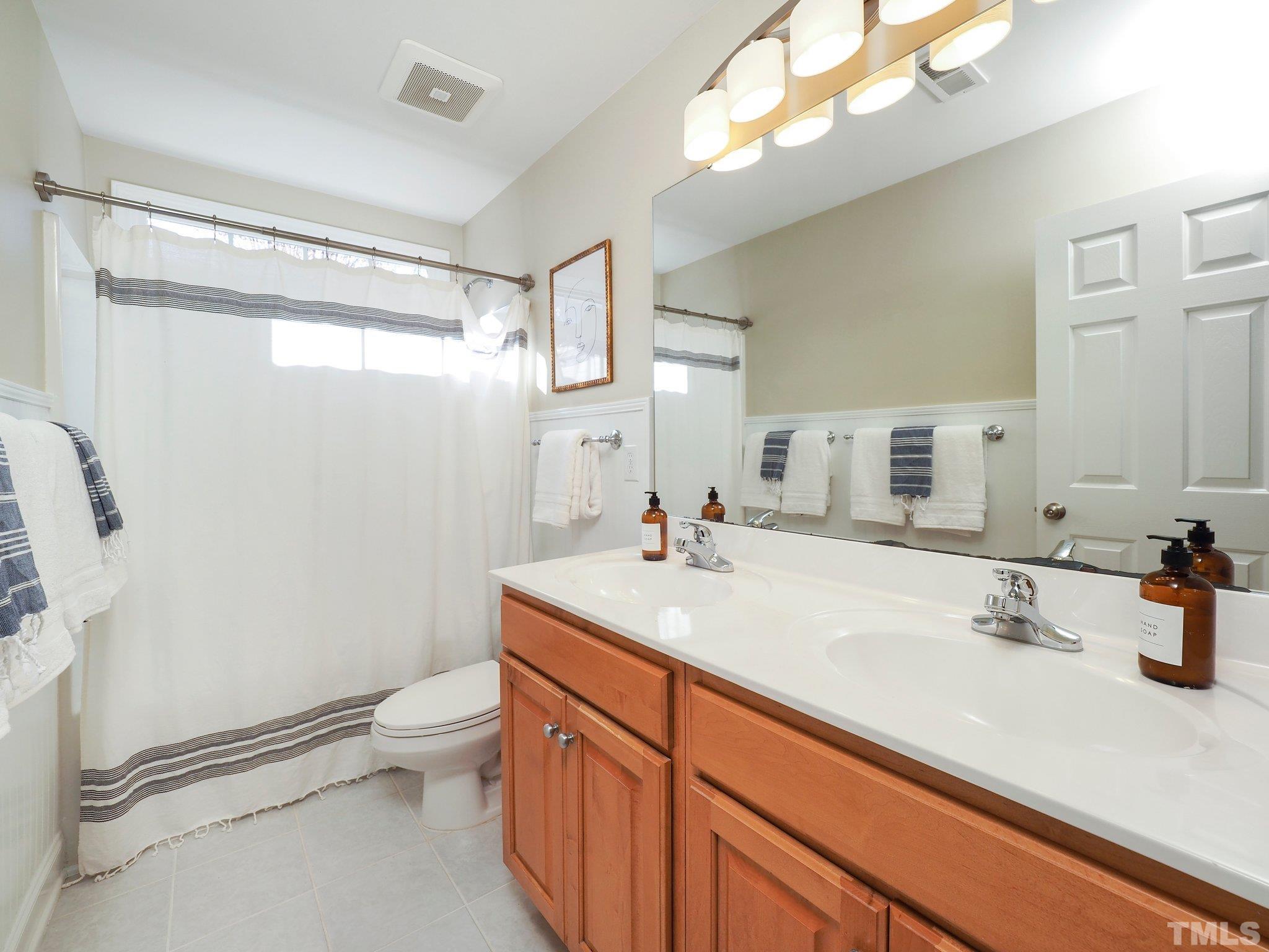 703 Haddon Hall Drive Apex, NC 27502 - Photo 33 of 49 a bathroom with a sink a toilet a mirror and shower
