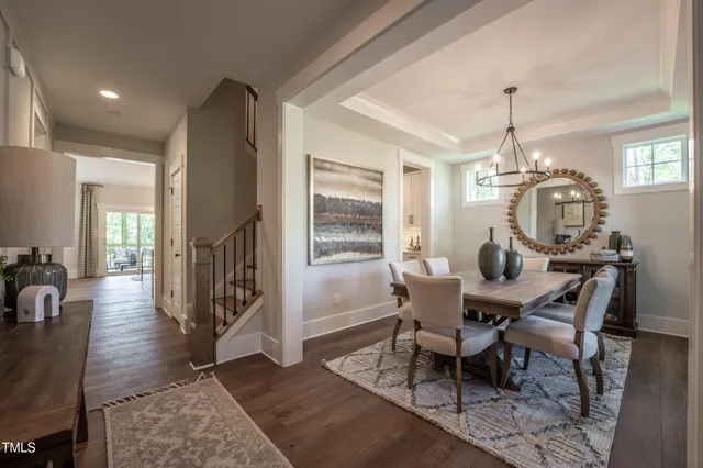 a dining room with wooden floor a chandelier a wooden table and chairs