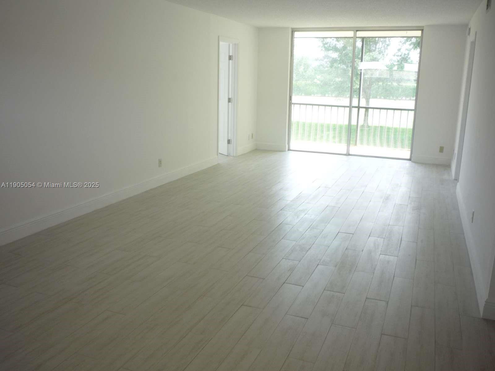9520 South Hollybrook Lake Drive, Unit 205 Pembroke Pines, FL 33025 - Photo 4 of 22 an empty room with wooden floor and windows